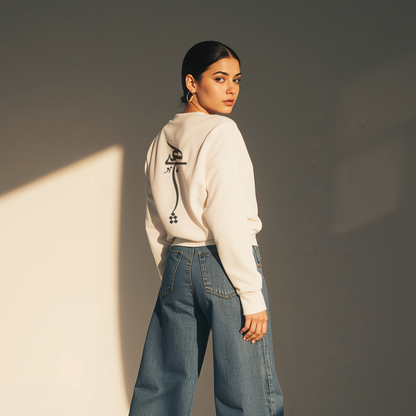 Person wearing a light-colored hoodie and blue jeans against a plain background